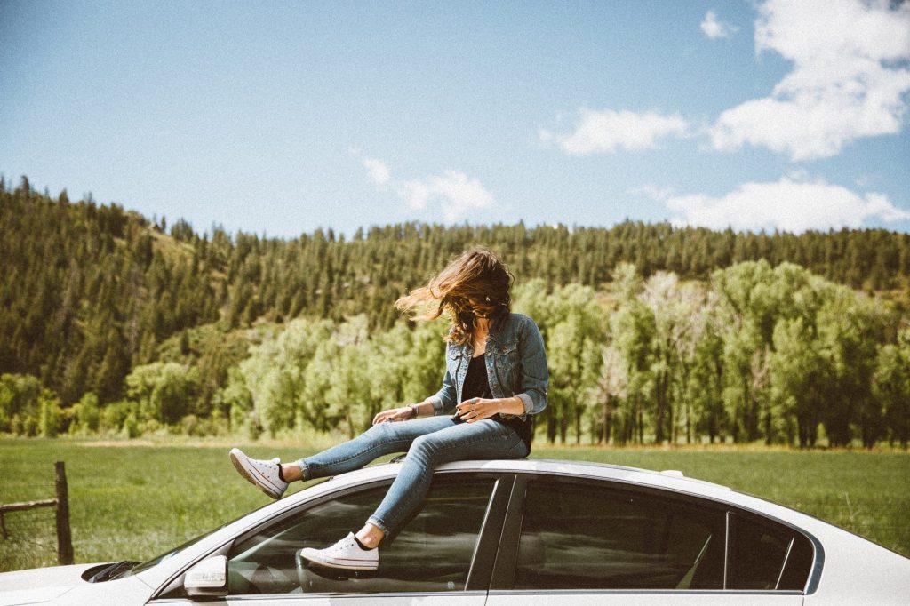 Une personne assise sur le toit d'une voiture à la campagne