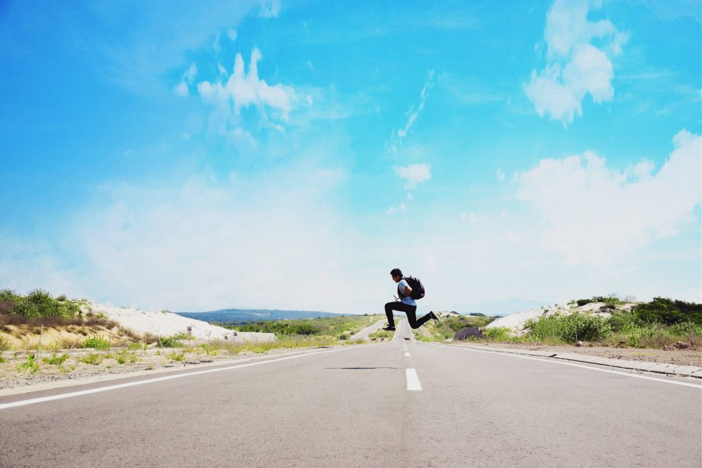 une homme traversant une route avec un sac à dos de voyage