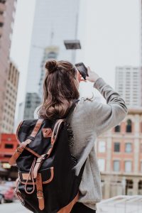 Jeune voyageuse avec sac à dos en train de prendre en photo la ville qu'elle visite