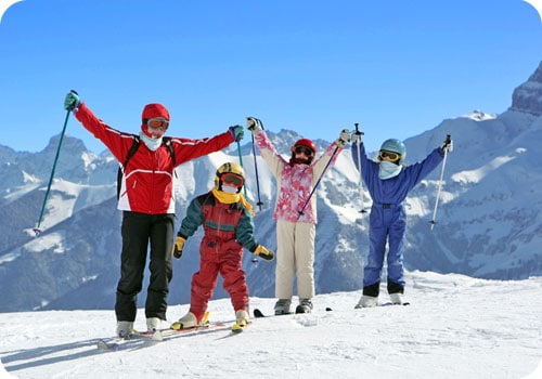 famille en vacances au ski posant avec skis et bâtons 